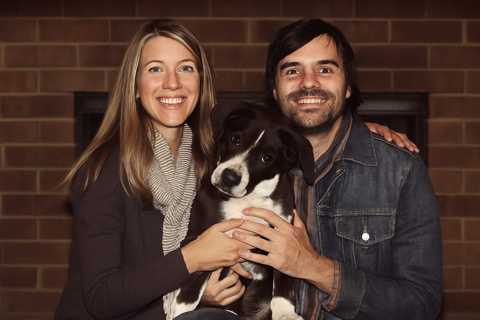 Happy young couple smiling while holding their adopted puppy, Layla.