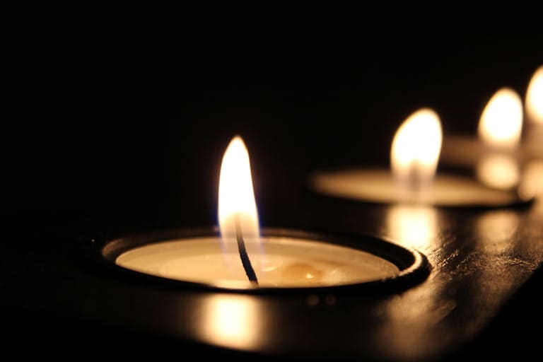 Close-up of glowing candle flames in the dark, creating a warm ambiance.